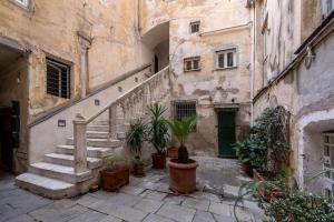 an old building with stairs and potted plants in a courtyard at Palazzo dei Rolli Charm [Centro Storico di Genova] in Genova
