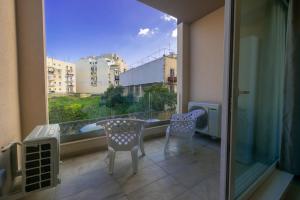 d'un balcon avec une table, des chaises et une fenêtre. dans l'établissement Spacious Brand New Apartment 3 Bdr 2 Bth Large Terrace, à San Pawl il-Baħar