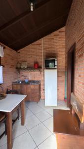 a kitchen with a white refrigerator and a brick wall at Pousada Parque da Cachoeira in São Francisco de Paula