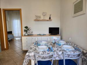 a dining room with a table with plates and chairs at Appartamento Caracola in Lignano Sabbiadoro