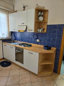 a kitchen with white cabinets and blue tiles at Appartamento Caracola in Lignano Sabbiadoro
