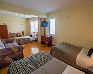 a hotel room with two beds and a table at HOTEL DACARLO in Santiago