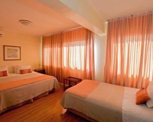 HOTEL DACARLO في سانتياغو: غرفة فندقية بسريرين ونافذة