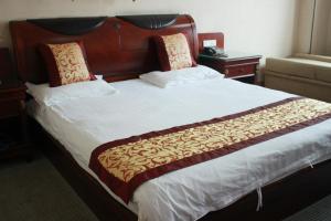 Schlafzimmer mit einem großen Bett mit einem Kopfteil aus Holz in der Unterkunft Taizhou Taishan Business Hotel in Taizhou