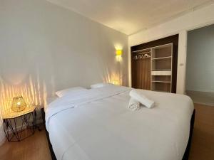1 dormitorio con 1 cama blanca grande y 2 toallas en Appartement Lumineux 3 chambres, en Marcq-en-Baroeul