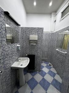 uma casa de banho com um lavatório e uma parede em azulejo em Hotel Nelson - Bab El Oued em Bab el Oued