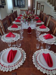 una mesa larga con servilletas rojas y gafas. en Aconchego Mineiro, en São João del Rei