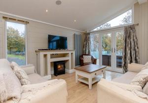 a living room with two white couches and a fireplace at Loch Lomond Holiday Park in Inversnaid