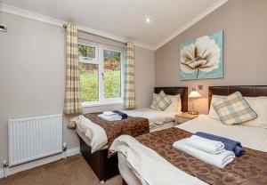 sypialnia z 2 łóżkami i oknem w obiekcie Loch Lomond Holiday Park w mieście Inversnaid