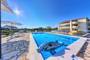 a swimming pool with a dolphin in the middle at Apartments CVITA Holiday in Rogoznica