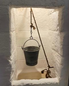 a black bucket hanging from a brick wall at La Ramasola in Fasano