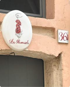 een bord aan de zijkant van een gebouw met een bos druiven bij La Ramasola in Fasano