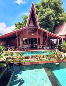 a house with a swimming pool in front of a house at Kaleydo Villas in Gili Trawangan