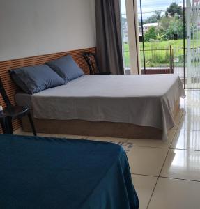 a bedroom with a bed with blue pillows and a balcony at Casa das Embaúbas 1 in São José