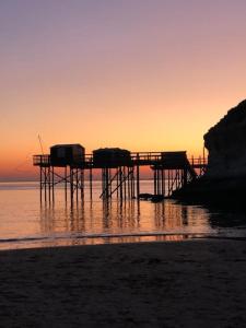 a pier on the beach with the sun setting at Maison de vacances avec piscine , dans résidence in Meschers-sur-Gironde