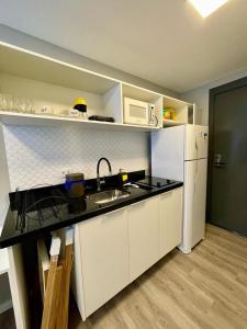 La cuisine est équipée d'un évier et d'un réfrigérateur blanc. dans l'établissement Admiravel, Studio Completo c/ Wifi e Ar Cond., à Curitiba