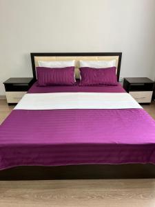 a large bed with purple sheets and pillows at Евродвушка in Kokshetau +2 photos