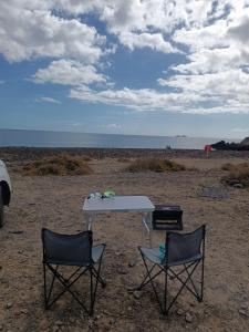una mesa y dos sillas en la playa en FurgoCamper Van H1, en Tetir