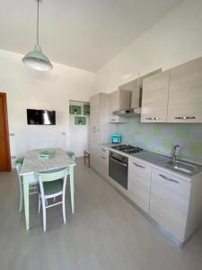 cocina con mesa y cocina con armarios blancos en Casa Vacanze Villa Annamaria, en Scanzano Jonico