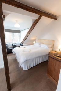 Un dormitorio con una gran cama blanca y un sofá. en Prospect House, en Whitby