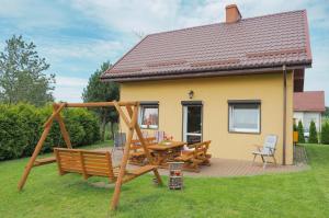 a house with a wooden deck with a table and chairs at Domki Letniskowe Cessatio Rusinowo in Rusinowo