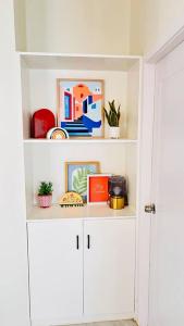 a white book shelf with plants and pictures on it at Mid-Century Modern Charm in Discovery Bay