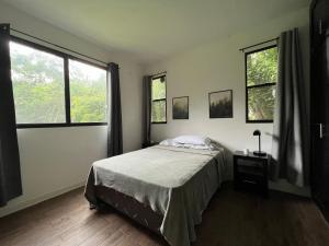 a bedroom with a bed and two windows at Casa Totumbla in Estelí