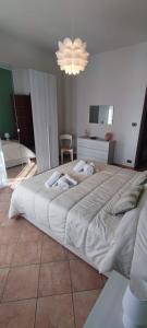 un grande letto bianco in una camera da letto con lampadario a braccio di L'ORCHIDHEA APARTMENT a Savigliano