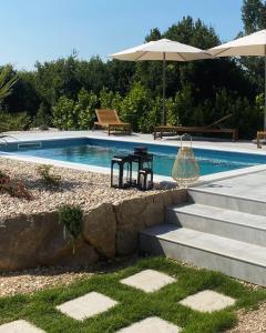 einen Pool mit einem Tisch und einem Sonnenschirm in der Unterkunft Meridiem Holiday Home in Dubrovnik region in Gruda