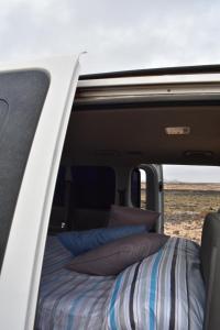 una cama en la parte trasera de una furgoneta con almohadas en FurgoCamper Van H1, en Tetir