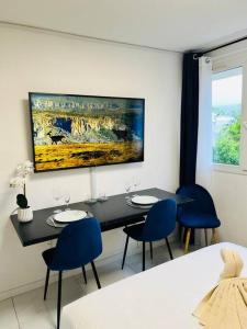 uma sala de jantar com uma mesa e cadeiras azuis em T1 - Le Papangue 5* - neuf, vue jardin, 8’ airport em Sainte-Clotilde