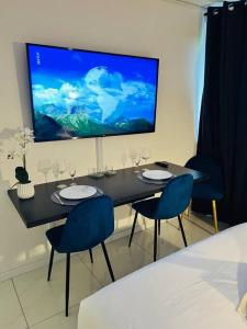 uma mesa de jantar com cadeiras e uma grande televisão na parede em T1 - Le Papangue 5* - neuf, vue jardin, 8’ airport em Sainte-Clotilde