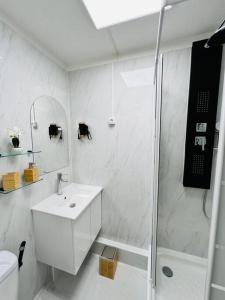 uma casa de banho branca com um lavatório e um chuveiro em T1 - Le Papangue 5* - neuf, vue jardin, 8’ airport em Sainte-Clotilde