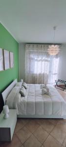 a large bed in a bedroom with a green wall at L'ORCHIDHEA APARTMENT in Savigliano