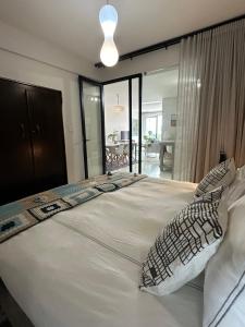 een groot wit bed met kussens in een slaapkamer bij Constantia View Apartments OPERATIONAL DURING LOADSHEDDING in Kaapstad