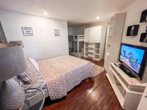 a small bedroom with a bed and a flat screen tv at Bambú Lodge San Jose Airport in Ciudad Cariari