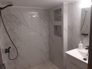 a white bathroom with a shower and a sink at Modern apartmen in Athina in Athens