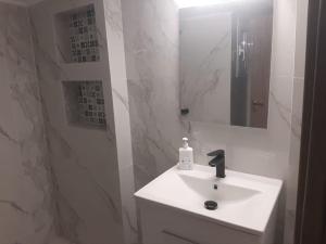 a white bathroom with a sink and a mirror at Modern apartmen in Athina in Athens
