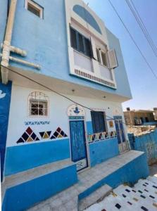 niebiesko-biały budynek z niebieskimi drzwiami w obiekcie Bakar House w mieście Aswan