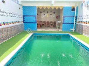 an indoor swimming pool with green and blue tiles at Bakar House in Aswan