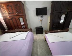 a bedroom with two beds and a flat screen tv at Bakar House in Aswan