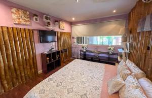 a bedroom with a large bed and a television at Bambú Lodge San Jose Airport in Ciudad Cariari