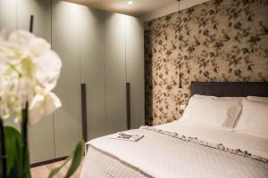 um quarto com uma cama com lençóis brancos e flores em NINARY APARTMENTS a due passi dal centro storico em Alba