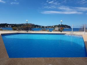 a large blue swimming pool next to a body of water at Mediterranean sea view apartment in Santa Ponsa