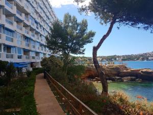 a walkway next to a building next to the water at Mediterranean sea view apartment in Santa Ponsa