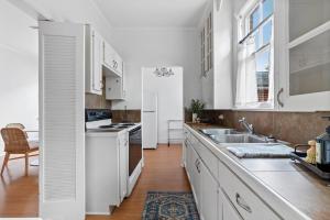 a kitchen with white cabinets and a sink at Large Groups Welcome - 2 Homes Next Door in New Iberia