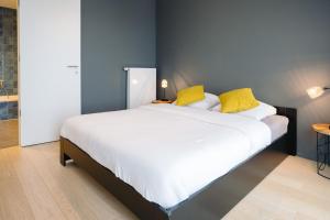 a bedroom with a large bed with yellow pillows at Vakantieappartement Oosteroever Oostende in Ostend