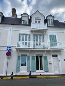 Edificio blanco con persianas azules y balcón en Superbe Studio avec vue sur la mer à 180° en Villers-sur-Mer