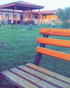 un banc en bois assis dans l'herbe près d'un bâtiment dans l'établissement Gamarah farm, à Al Wafrah
