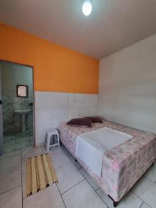 a bedroom with a large bed and a stool at Recanto Aconchego Itapoá in Itapoa
